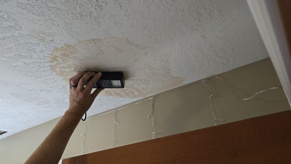 person assessing water damage on ceiling